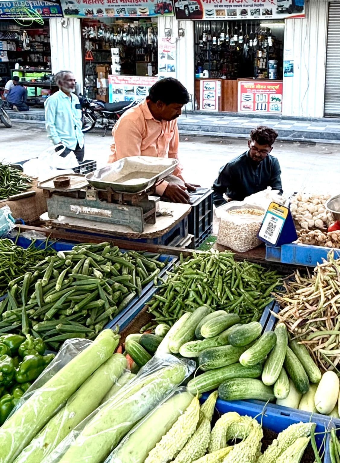 A vegetable vendor at his stall talking with a Nukaazo team member